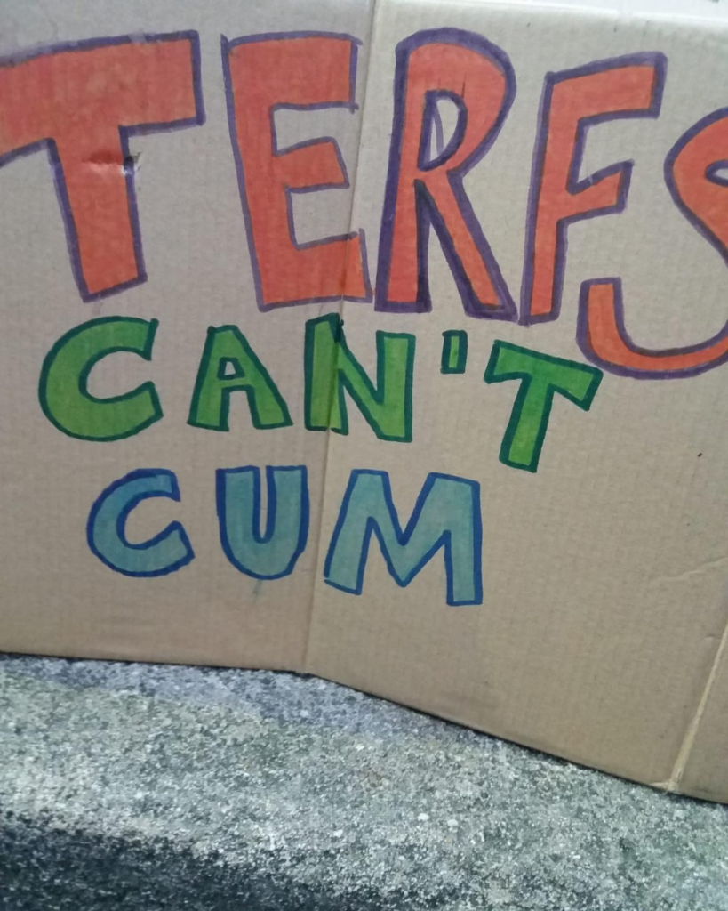 Cardboard sign with "TERFs can't cum" written on it