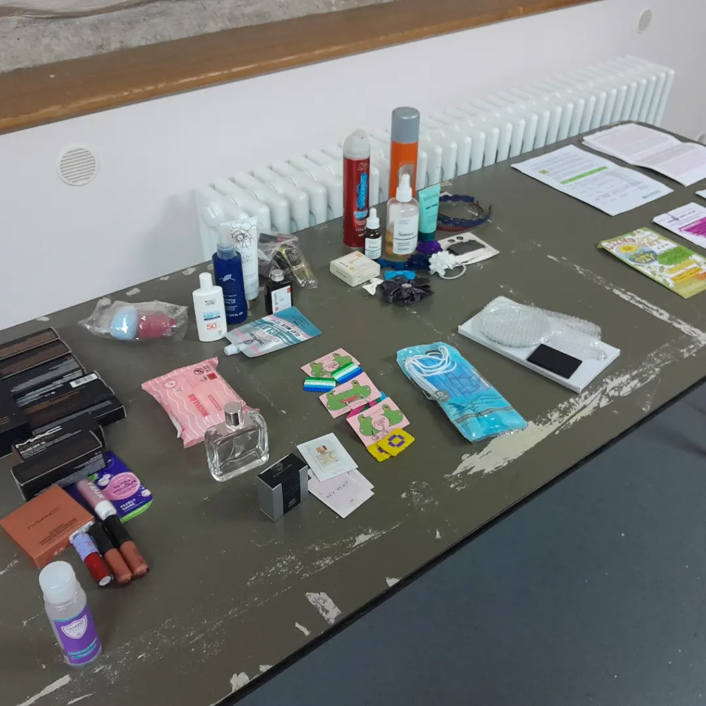 A large green table with varied cosmetics, products and leaflets on it.