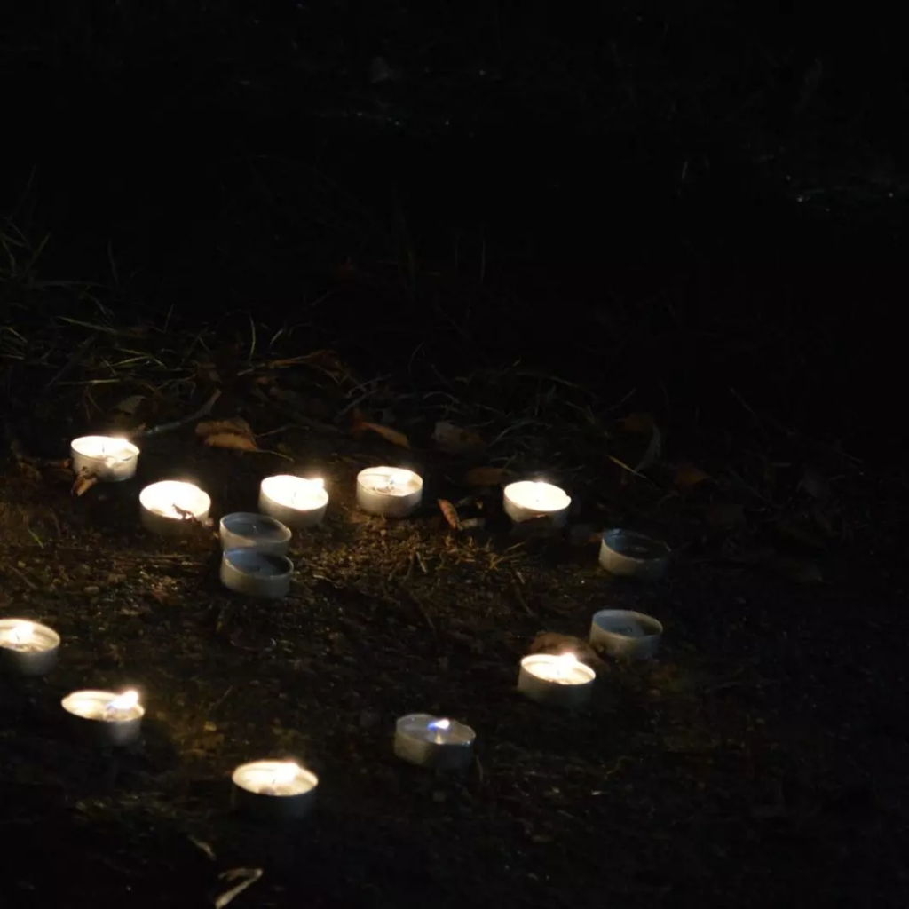 Tealights arranged in the shape of a heart on the ground.