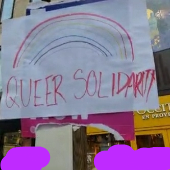 A sign with a rainbow drawn on it and "Queer Solidarity" written on it