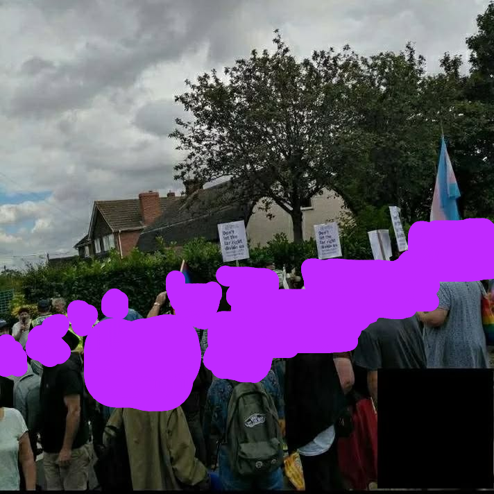 A group of people holding a trans flags and signs including "Don't let the far right divide us"