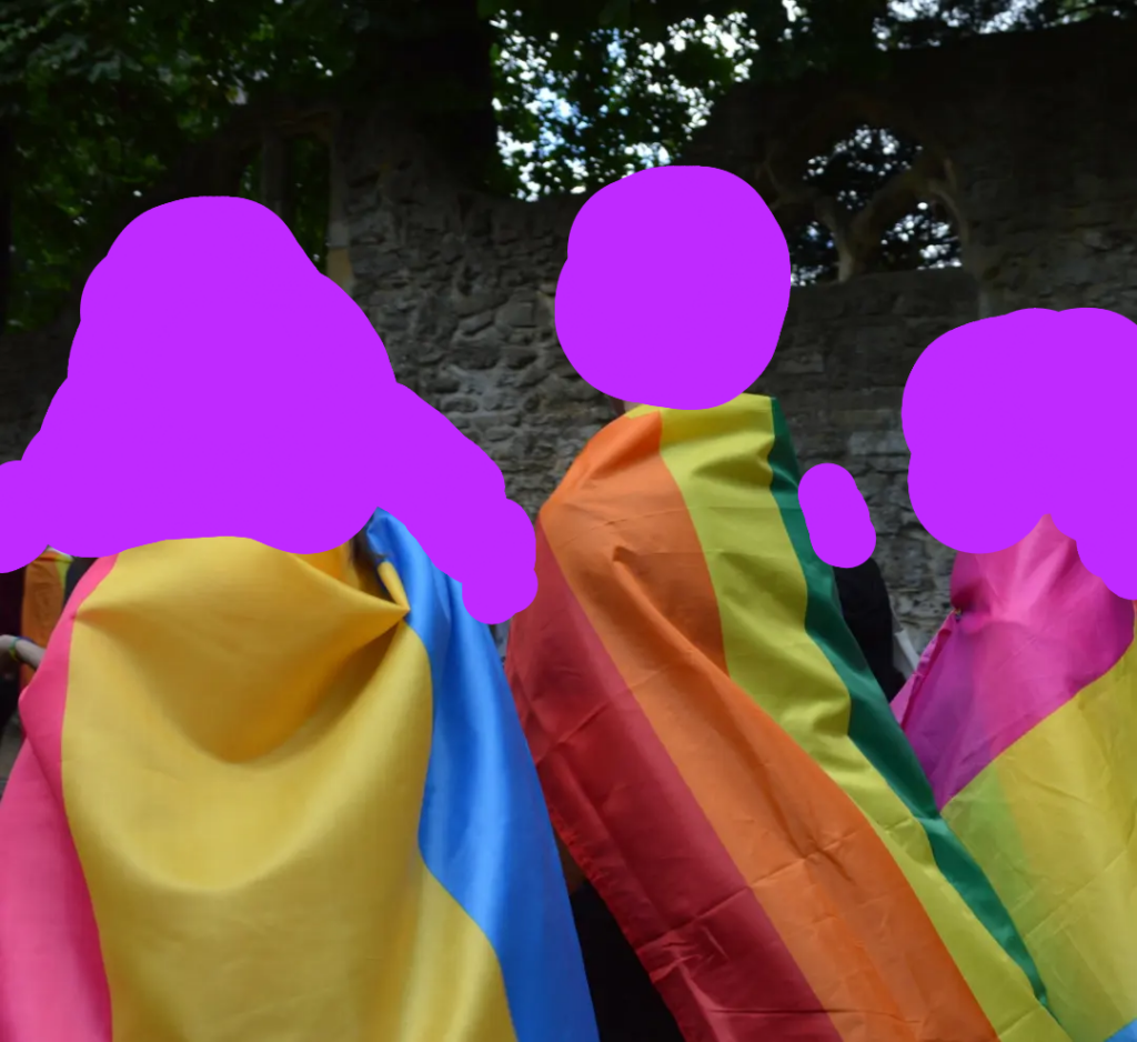 3 people wearing queer flags around their shoulders