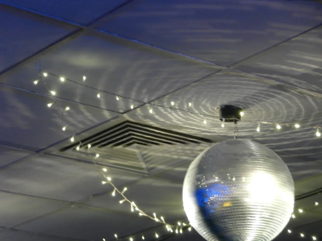 Photo of a disco ball hanging from the ceiling, surrounded by white fairy lights.