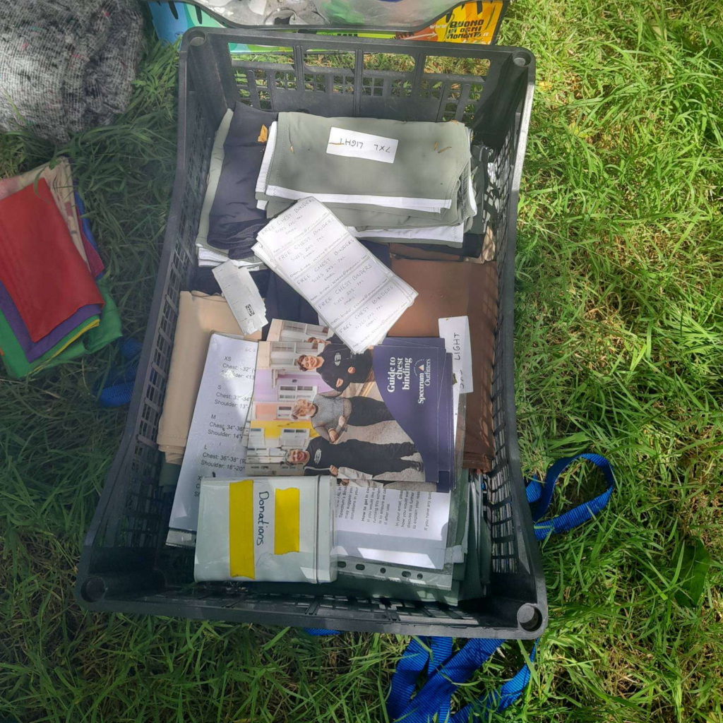 Black crate on the grass filled with binding resources, including binders, measuring guides and stickers.